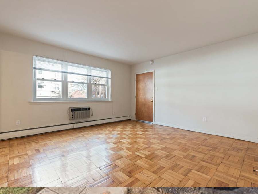 Living room area with hardwood floors and 3 windows in an apartment at Marlyn Apartments in Upper Darby, PA.