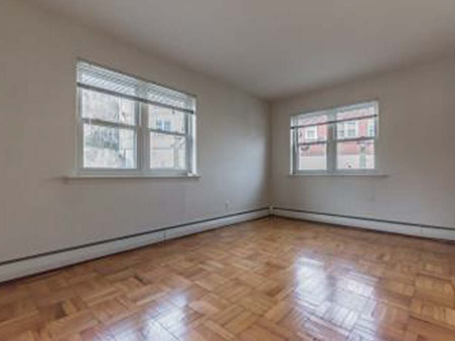 Living room with hardwood floors and 2 windows at Marlyn Apartments in Upper Darby, PA.
