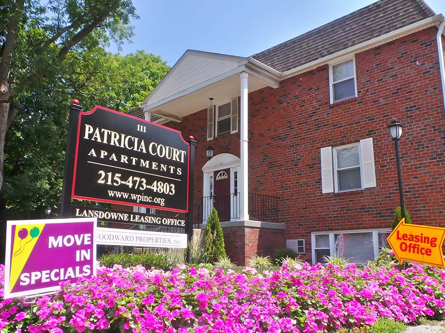 Exterior of Patricia Court apartments leasing office with floral landscaping.