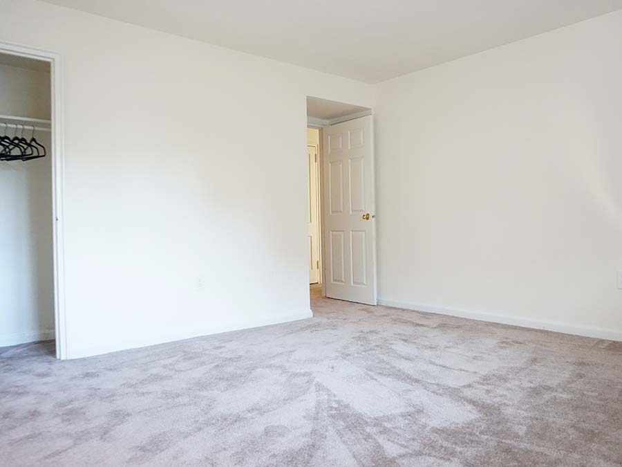 Carpeted bedroom with reach-in closet and door leading to a hallway at Penzel Manor apartments in Upper Darby, PA.