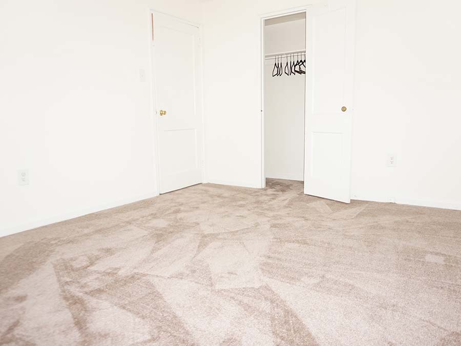 Tan carpeted bedroom with reach-in closet in Penzel Manor apartments in Upper Darby, PA.