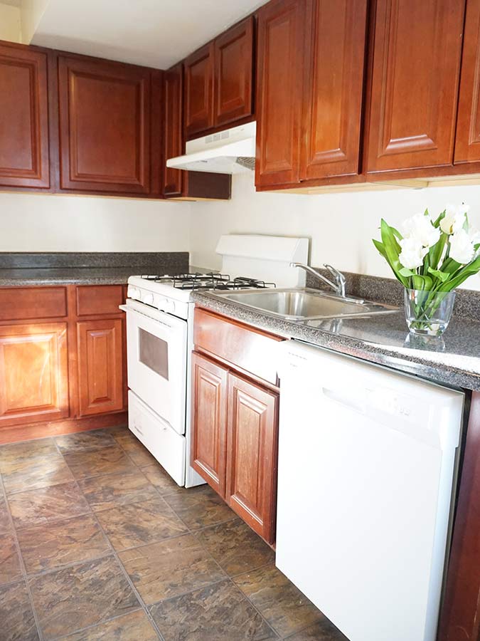 Large kitchen with darkwood cabinets and white appliances in Penzel Manor in Upper Darby, PA.