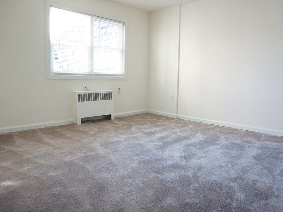 Carpeted bedroom with heating and a window in the Penzel Manor apartments in Upper Darby, PA.