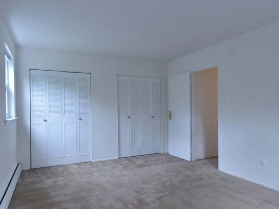 Carpeted bedroom with reach-in closet and window showing the large trees outside Ridgeway Court in Landsowne, PA.