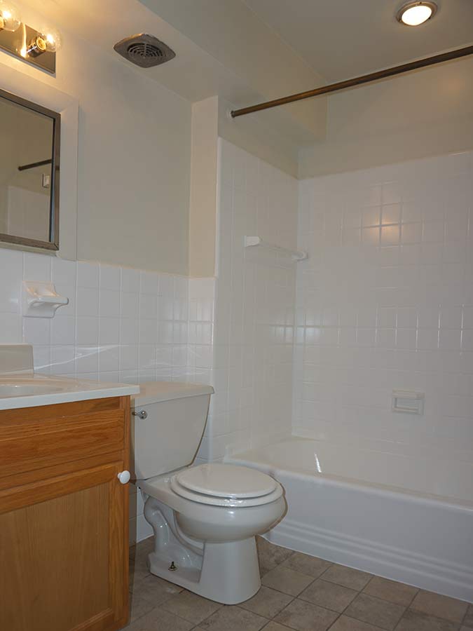 Large tiled bathroom with sink a medicine cabinet at Sheldrake Apartments in Upper Darby, PA.