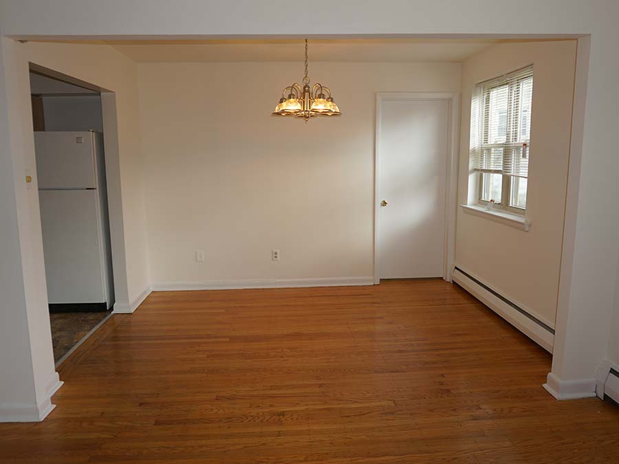 Dining area with hanging celing light and wood flooring leading to the kitchen at Sheldrake Apartments in Upper Darby, PA.