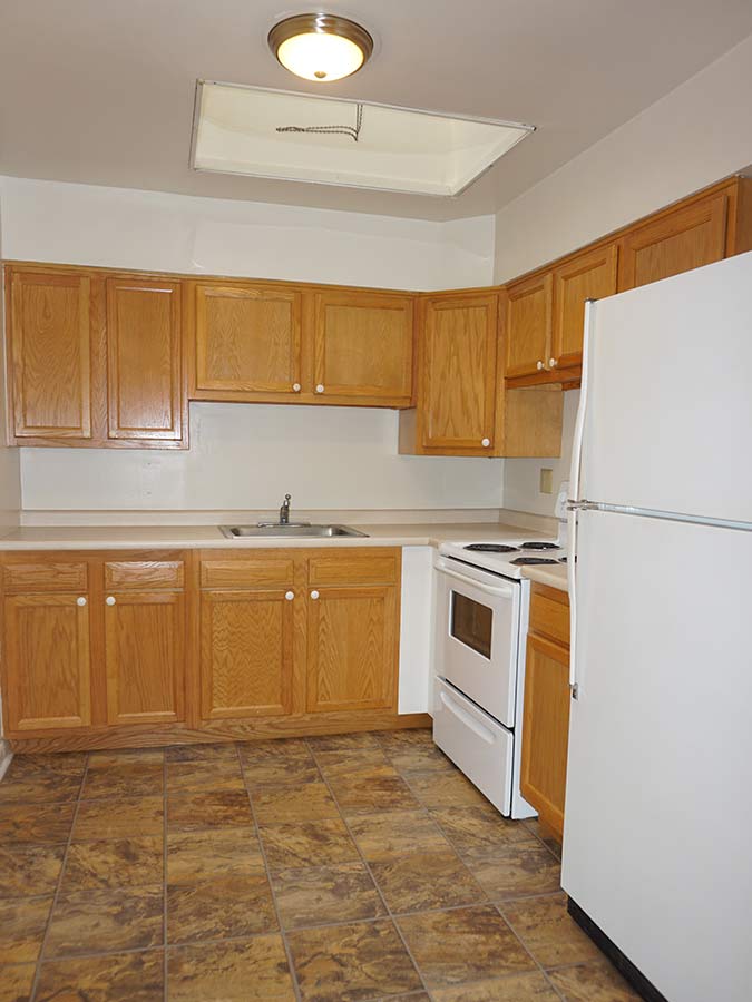 Spacious kitchen with lightwood cabinets and white appliances in Sheldrake Apartments in Upper Darby, PA.