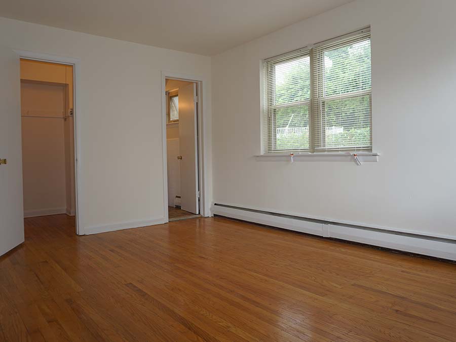 Master bedroom with wood floors and large windows at Sheldrake Apartments in Upper Darby, PA.