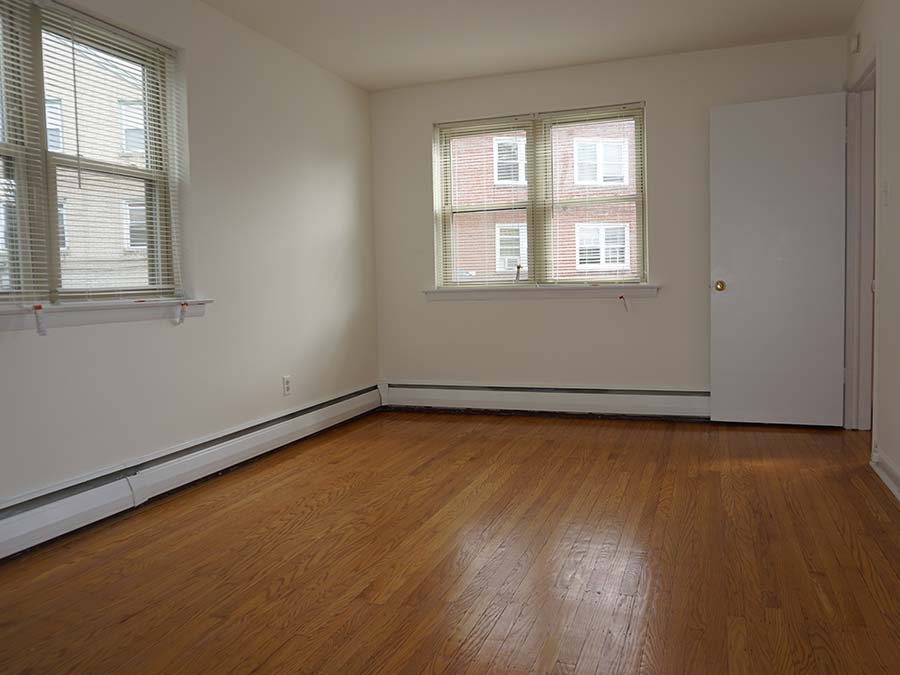 Bedroom with wood flooring and two windows and heating at Sheldrake Apartments in Upper Darby, PA.