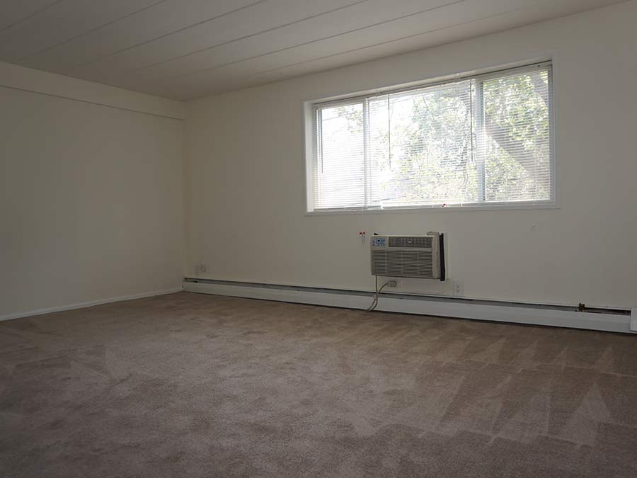 carpeted apartment living room at Ambassador Terrace with large window and air conditioner