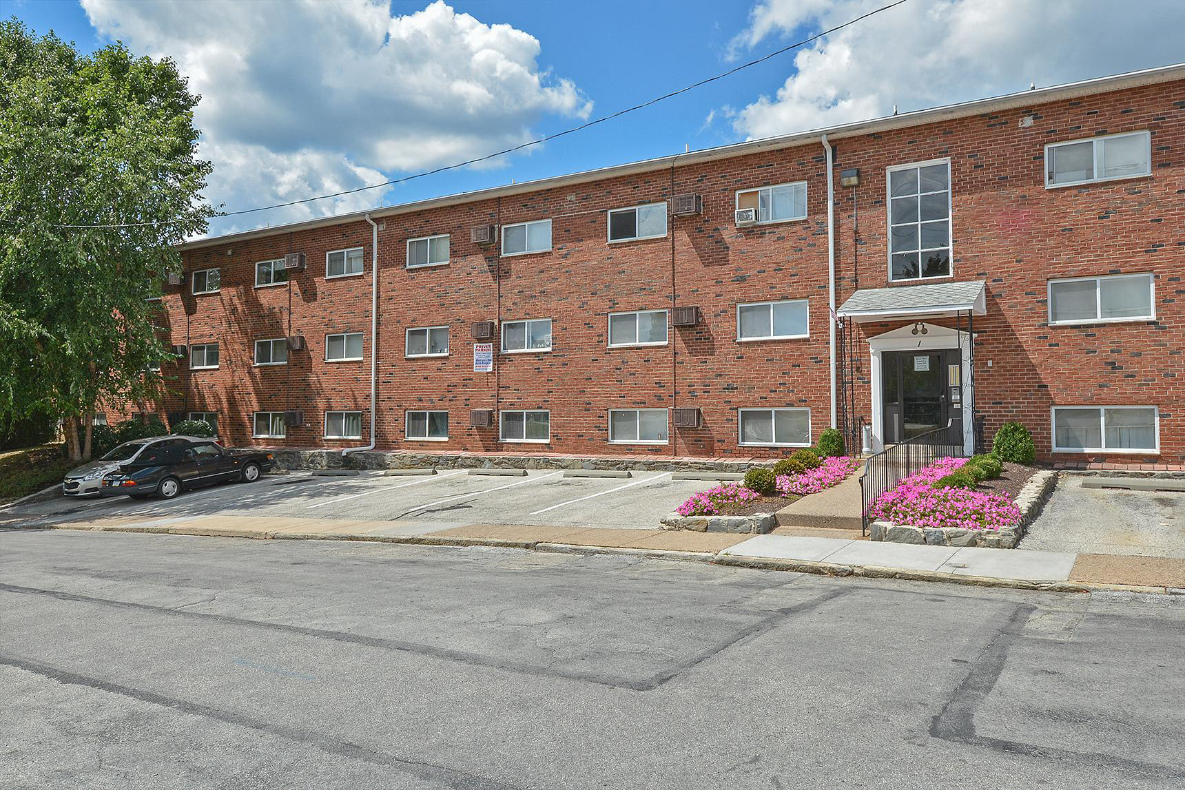 Exterior of Hazel Apartments with parking spaces in Clifton Heights, PA.