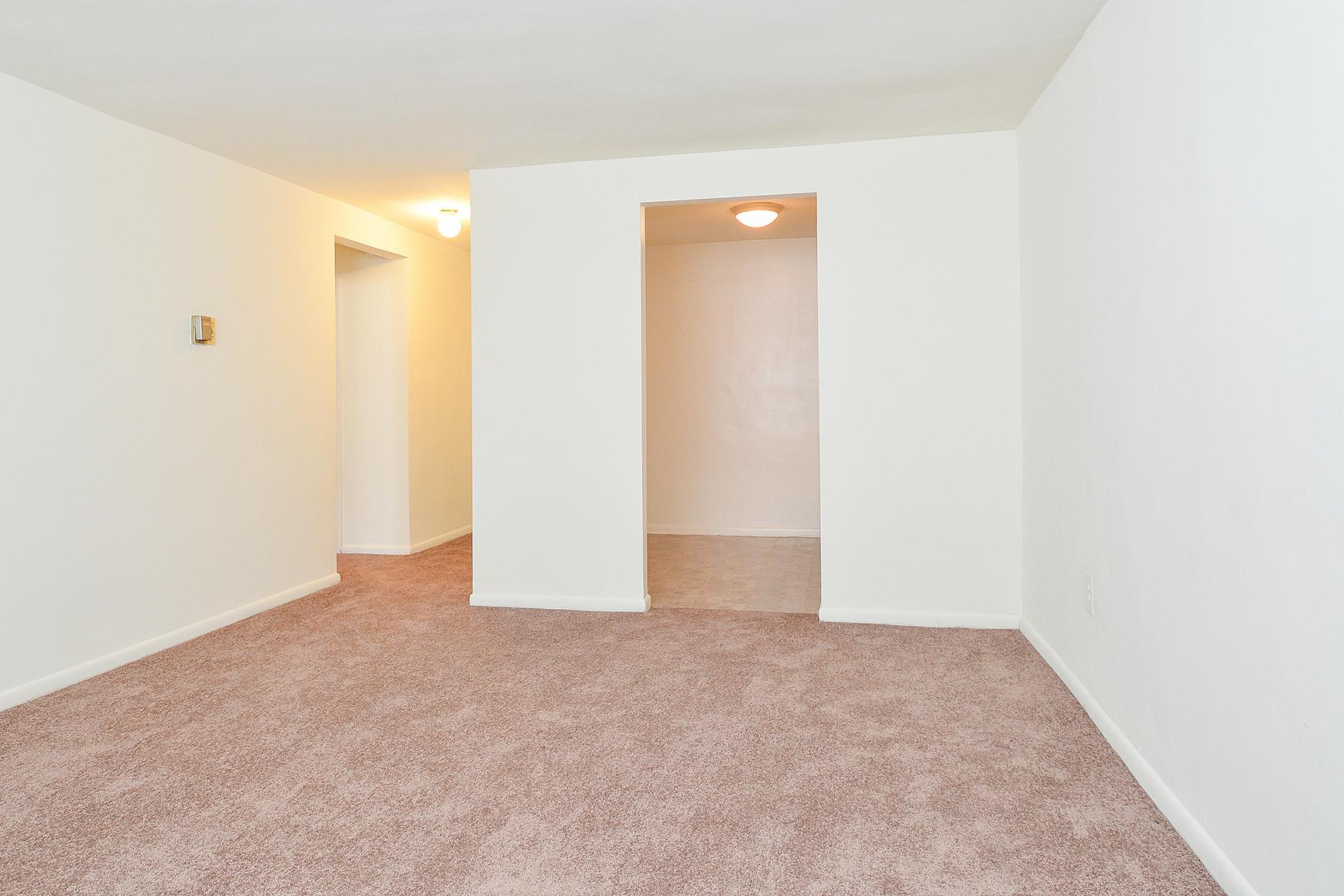 Spacious and carpeted living room space in an apartment at Hazel Apartments in Clifton Heights, PA.